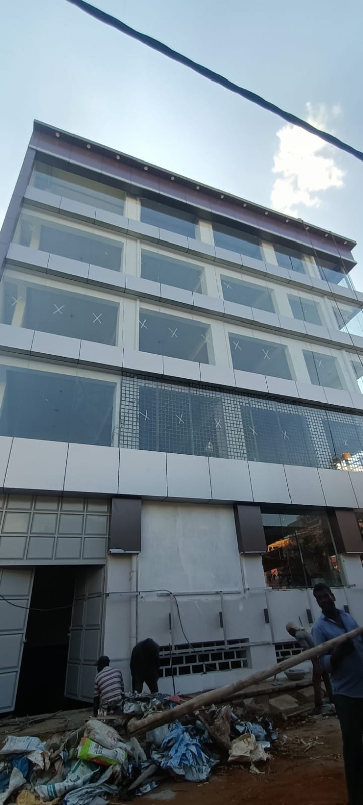 Modern Glass Office Building Design, exterior works by Dhrithi Infra